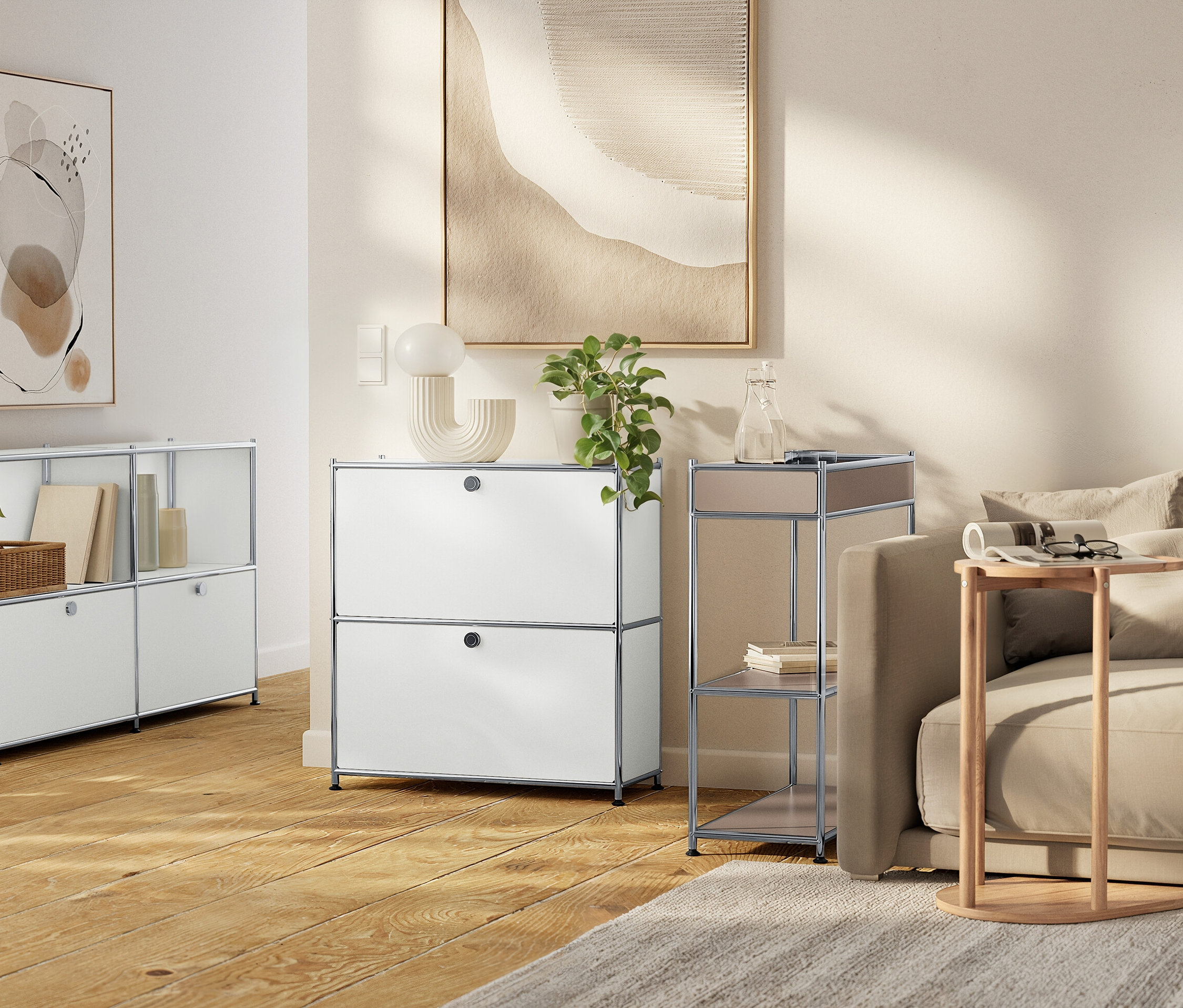 Obývací pokoj s bílými modulárními úložnými jednotkami, béžovou pohovkou a neutrálními uměleckými díly.