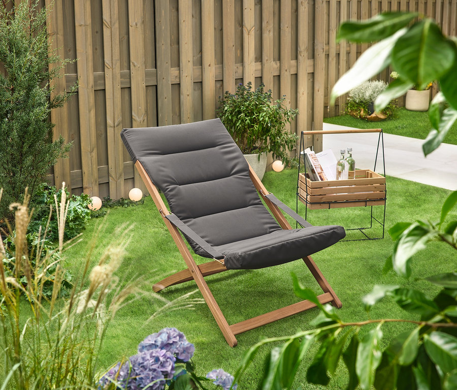 Na zeleném trávníku stojí truhlík na bylinky s držadlem na přenášení »Elin« vedle lehátka.