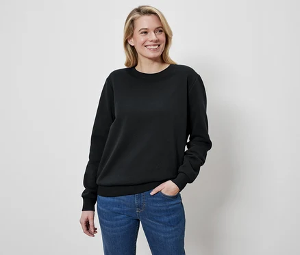 Žena s blond vlasy má na sobě černý svetr a džíny.
