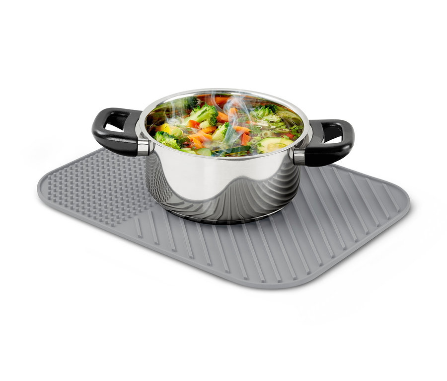 Nerezový hrnec plný zeleniny stojí na silikonovém odkapávači na nádobí.