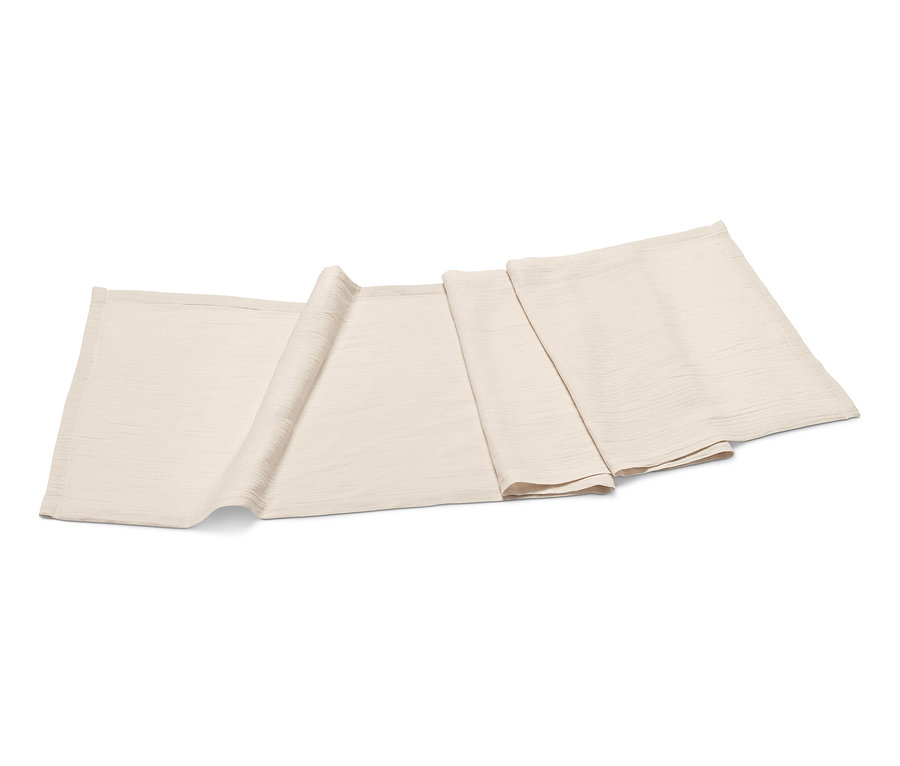 Béžový mušelínový běhoun na stůl leží složený na bílém pozadí.