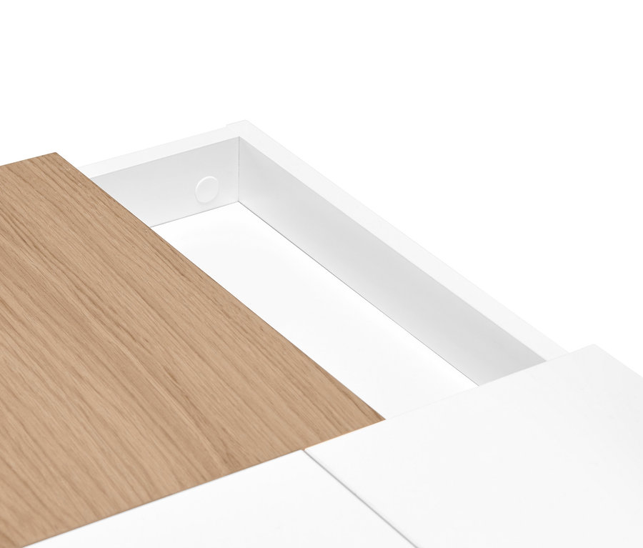 Detail bílého psacího stolu s výklopnými přihrádkami a dřevěnou deskou.