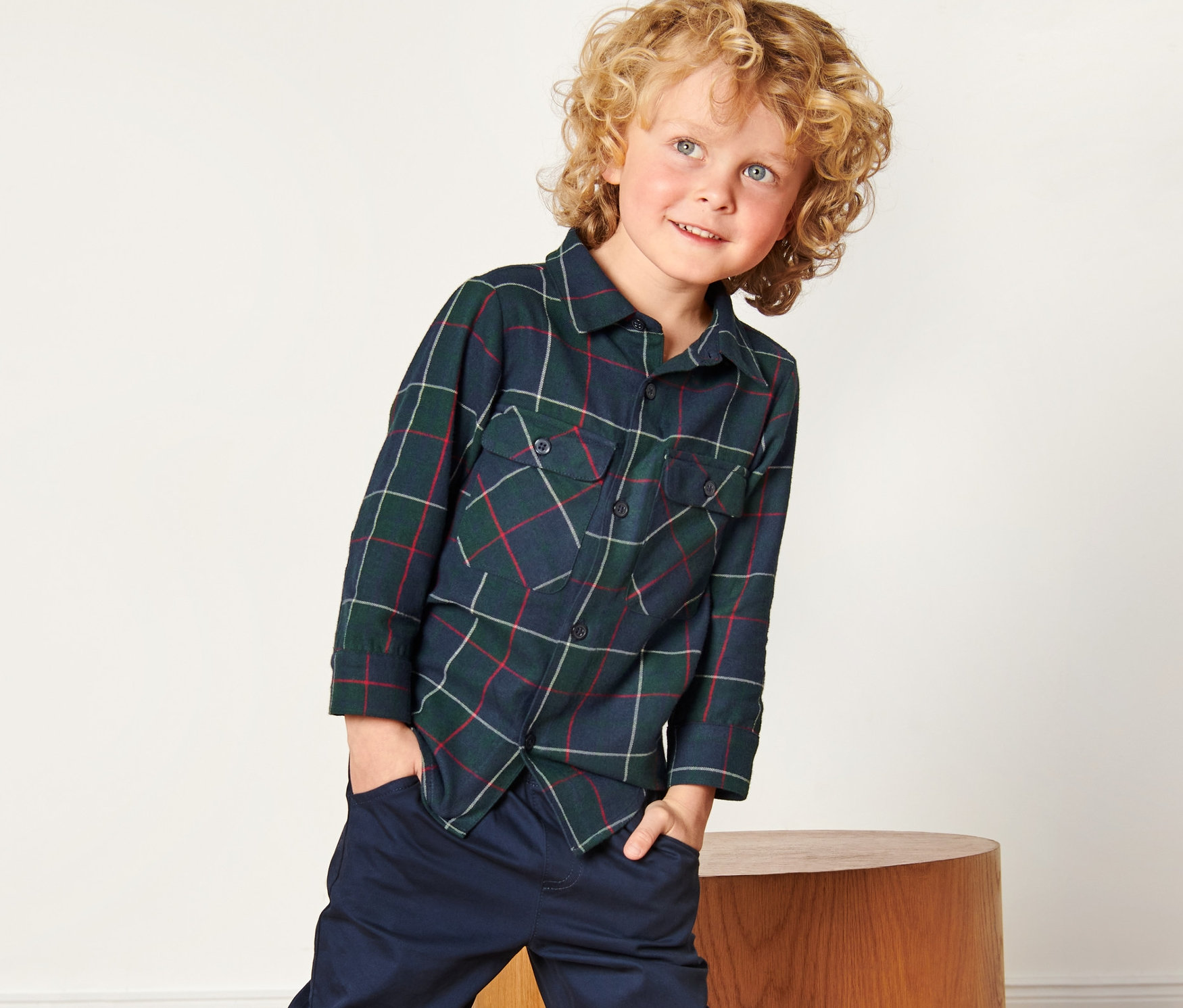 Chlapec v dětské flanelové košili s rukama v kapsách.