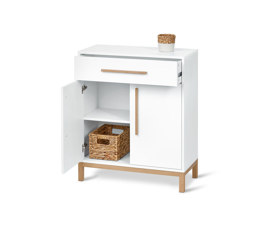 Bílá koupelnová skříňka s otevřenou zásuvkou a dvířky, uvnitř proutěný košík.