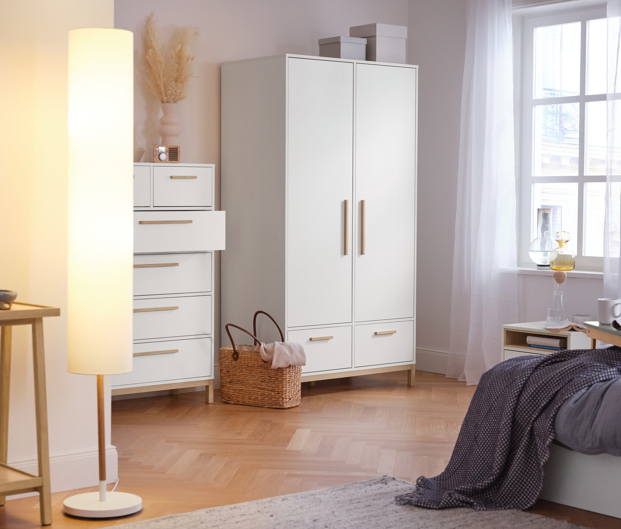 V ložnici stojí konzolový stolek se 2 odkládacími plochami, stojací lampa s textilním stínítkem, vysoká skříňka »Eklund« se zásuvkami a šatní skříň »Eklund« se zásuvkami.