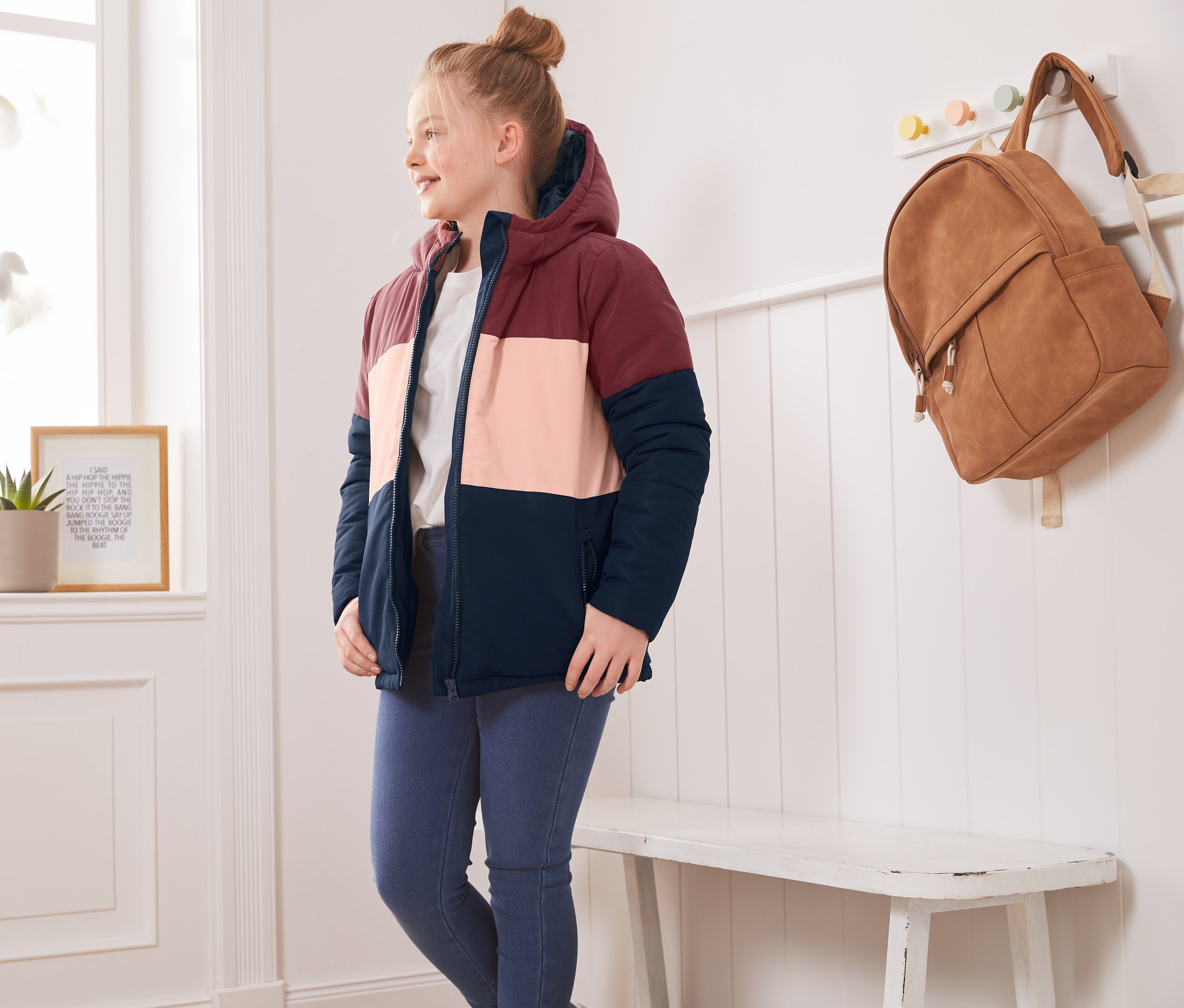 Dívka v termobundě ve stylu color blocking stojí v pokoji.