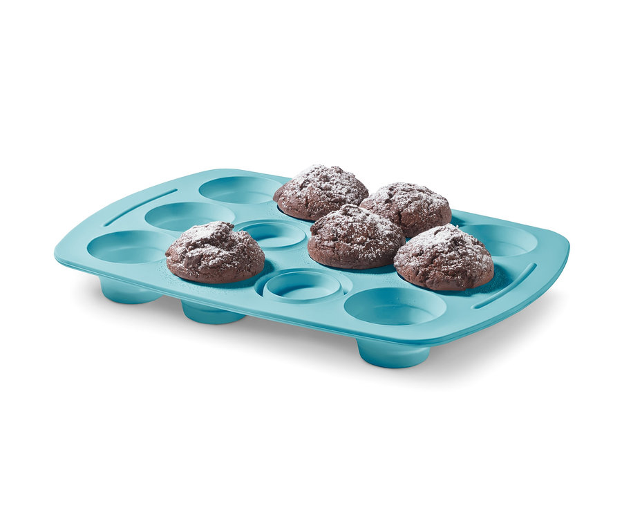 Pět muffinů s cukrem v modré silikonové formě na muffiny.