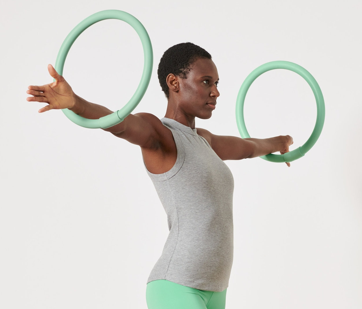 Žena cvičí s 2 obručemi na cvičení rukou.