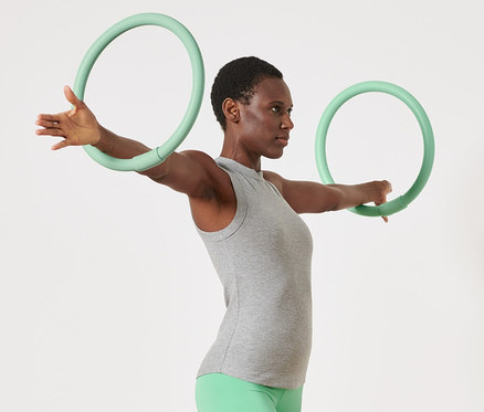 Žena cvičí s 2 obručemi na cvičení rukou.