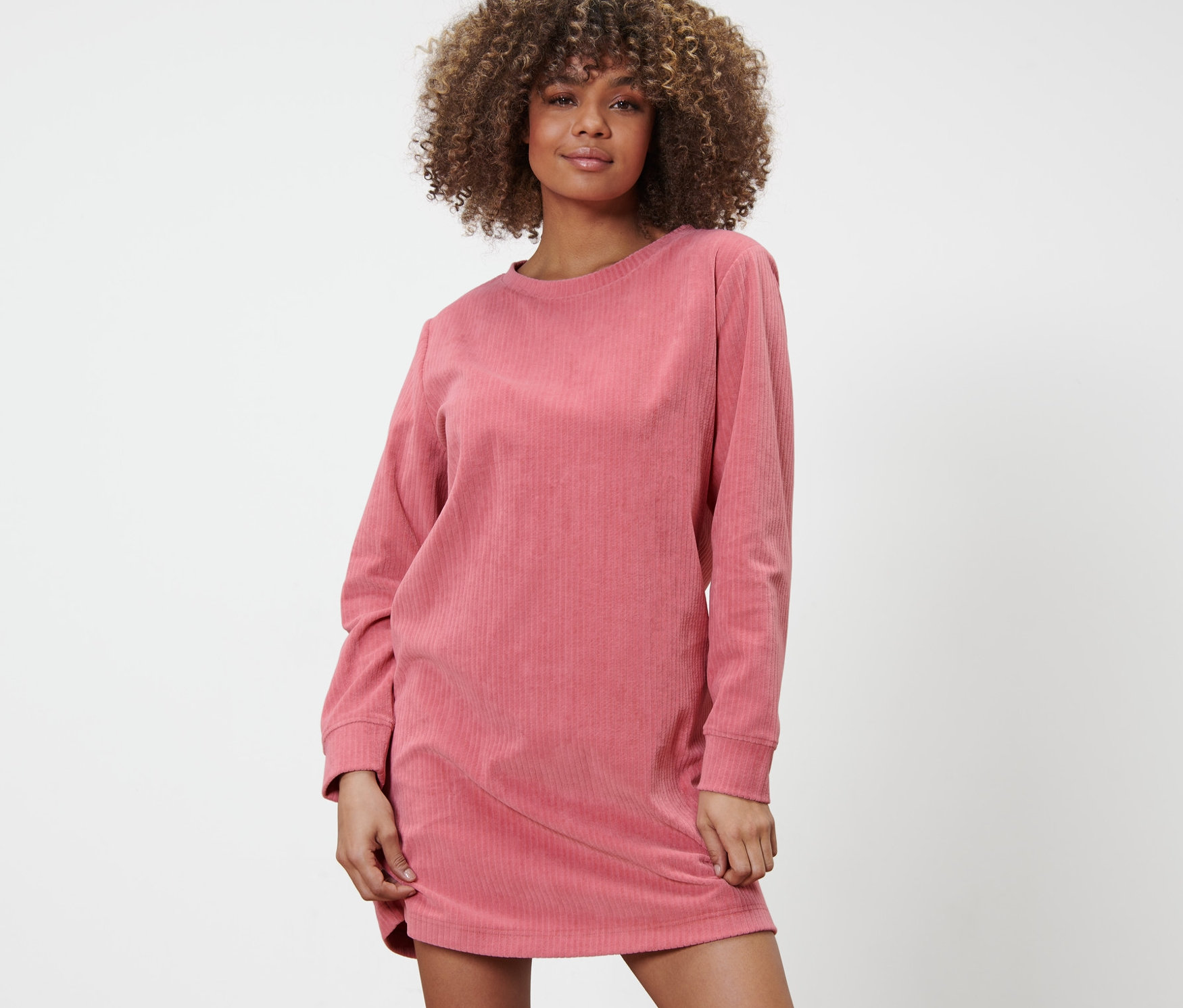 Žena pózuje v pohodlných šatech.