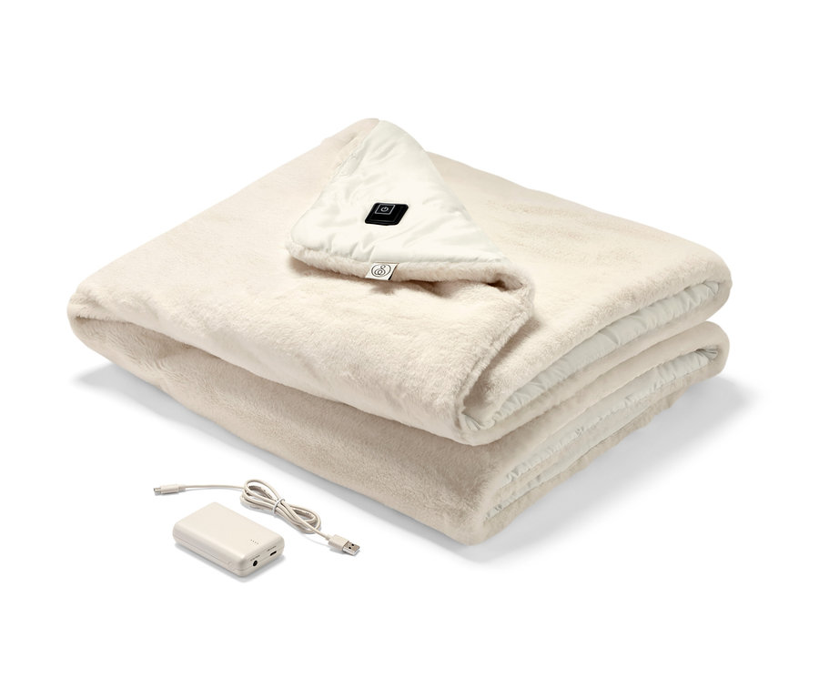 Složené vyhřívané pončo na baterie krémové barvy s viditelným ovládacím panelem a baterií.