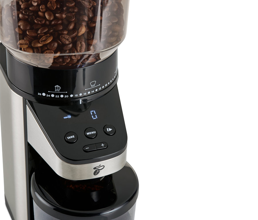 Detail elektrického mlýnku na kávu s váhou, s kávovými zrny nahoře.