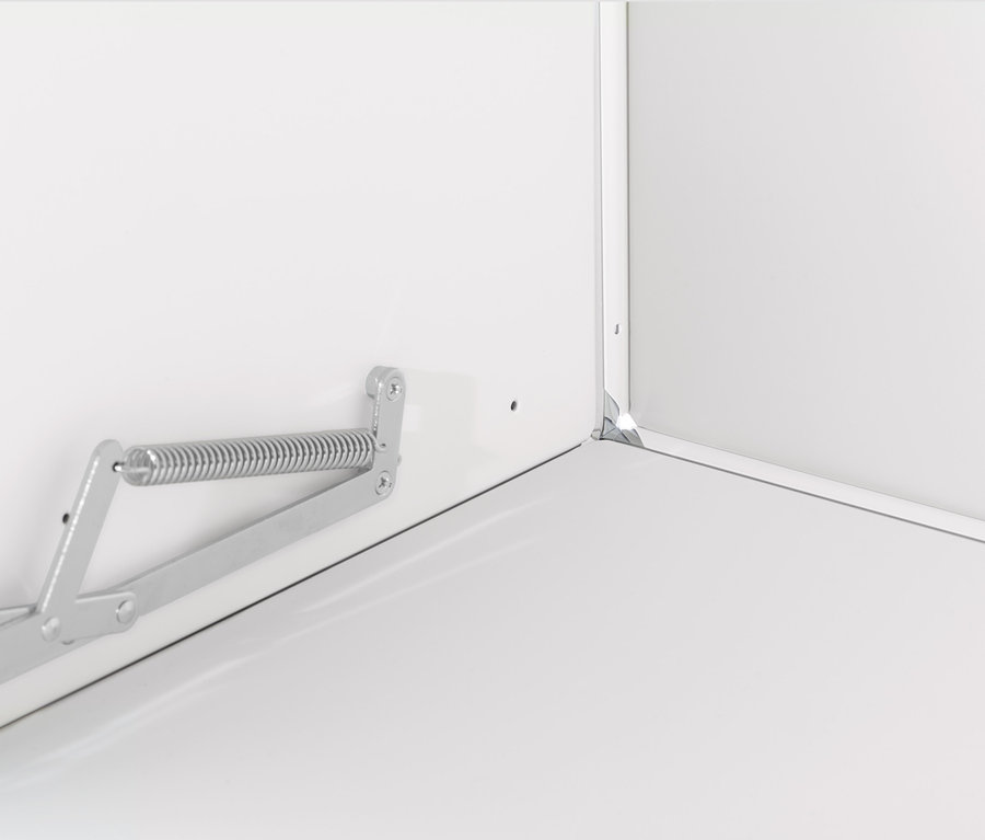 Detail bílé skříňky CN3 s kovovým mechanismem výklopných dvířek.