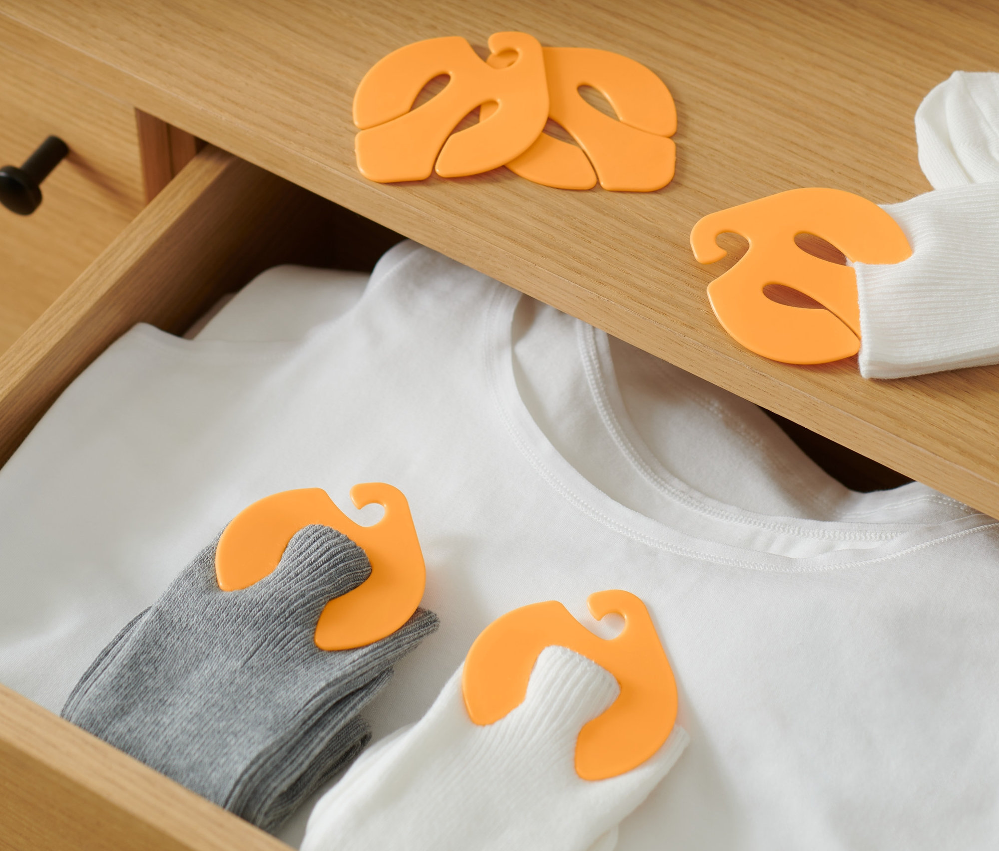 V zásuvce leží bílé tričko a ponožky spárované klipsy na ponožky, 20 ks.