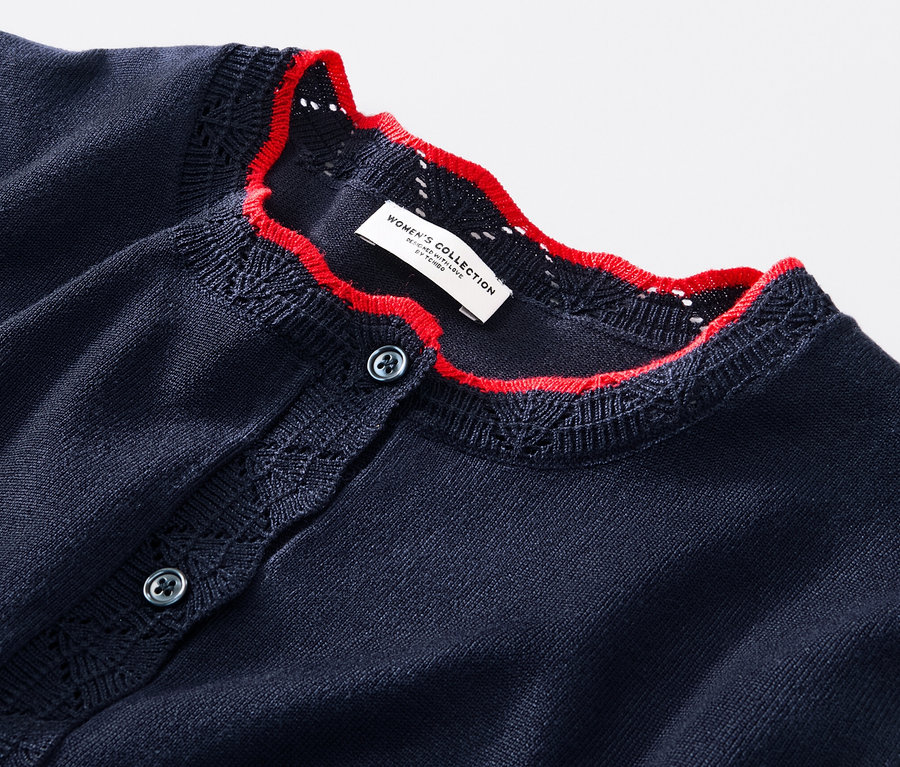 Detail svetru z jemného úpletu se zvlněným okrajem.