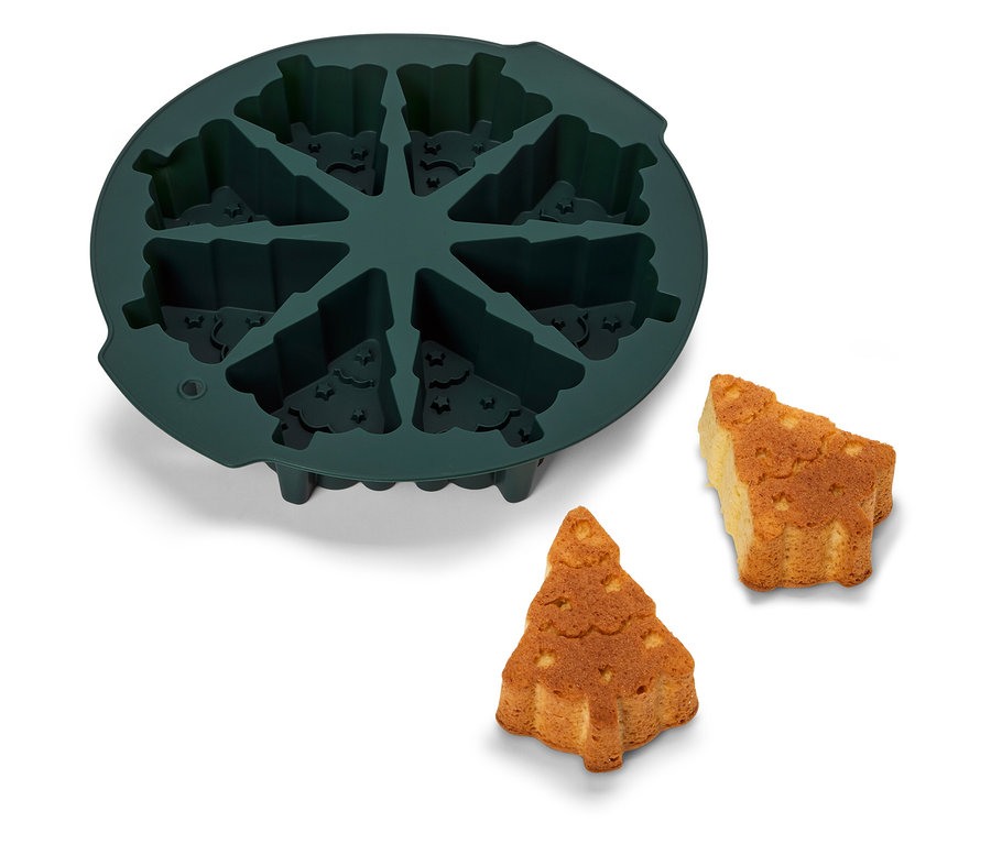 Zelená silikonová forma na pečení ve tvaru vánočního stromku s dvěma upečenými stromečky vedle.