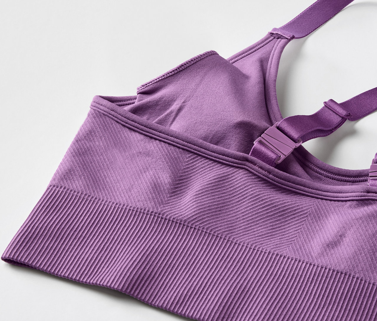 Detail fialové sportovní podprsenky s nastavitelnými ramínky.