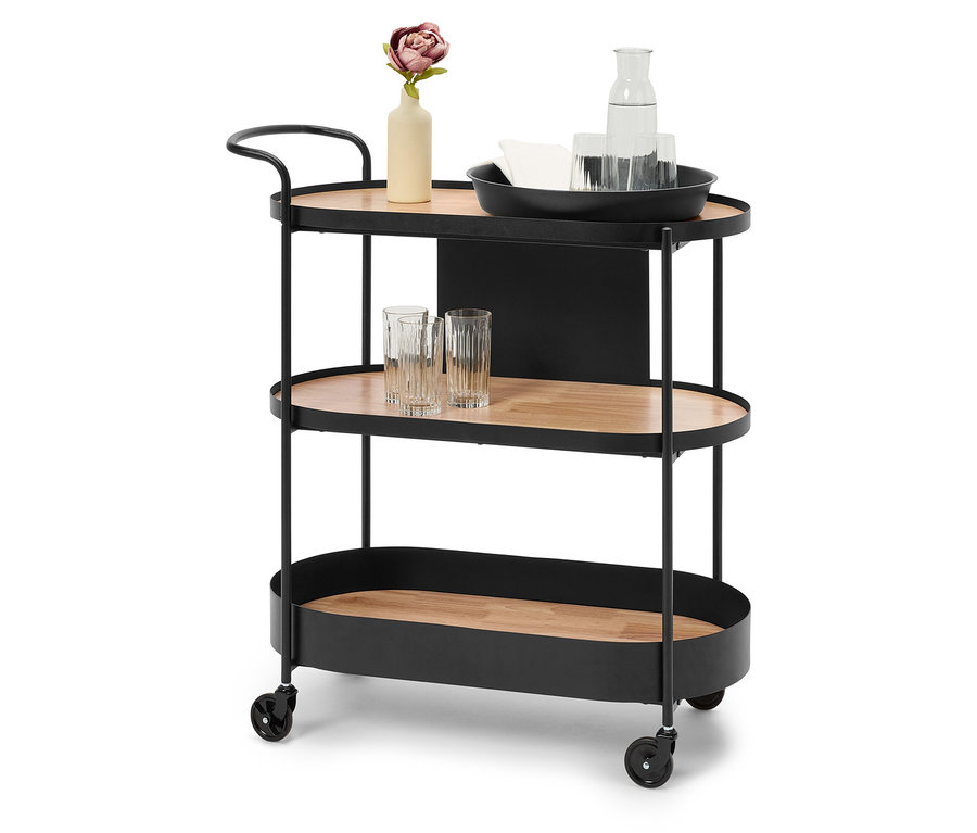Černý barový vozík se třemi policemi z hnědého dřeva, na horní polici váza s květinou, karafa s vodou a sklenice.