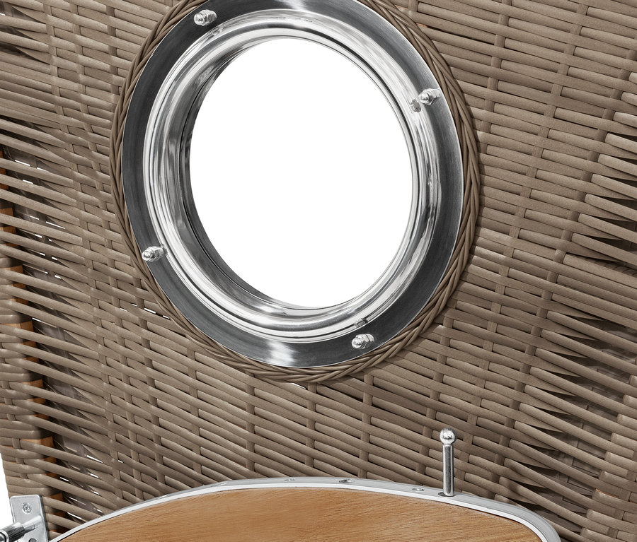 Detail proutěného plážového koše s kulatým okénkem s kovovým rámem.