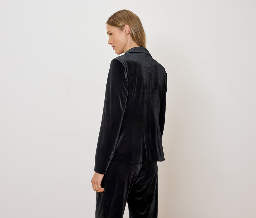 Žena má na sobě sametové sako a kalhoty.