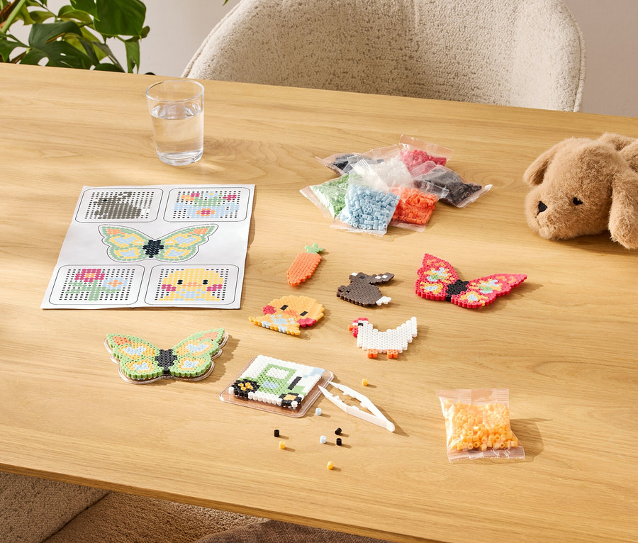 Stůl s korálkovou sadou, včetně šablon, hotových motivů a sortimentu barev v sáčcích.