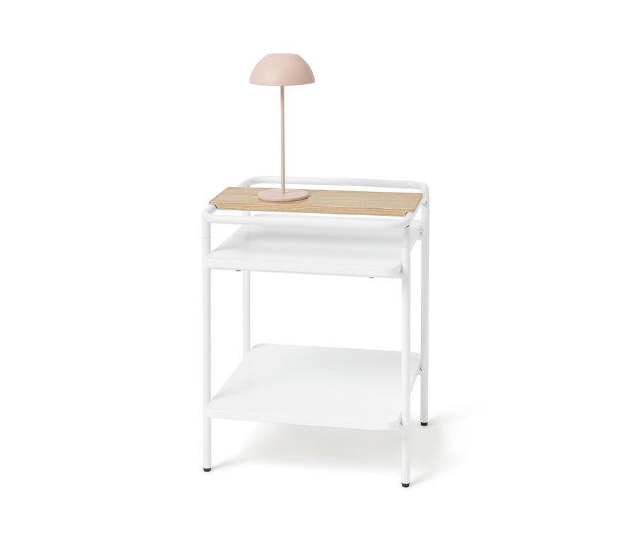 Bílý odkládací stolek se světlým dřevěným povrchem a růžovou lampou.