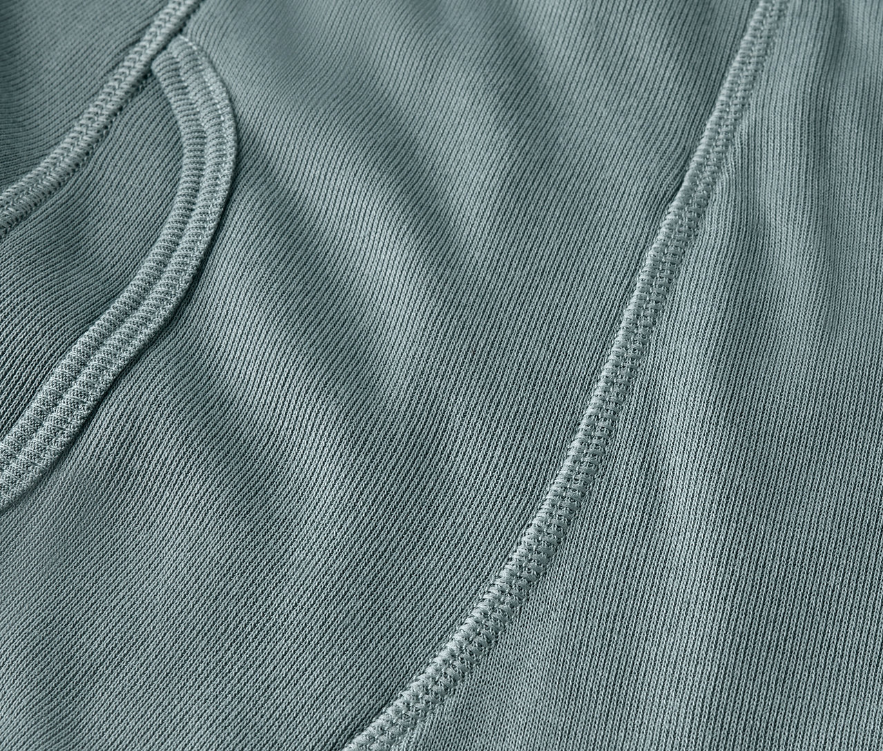 Detail šedozelené látky s kapsou a švem.
