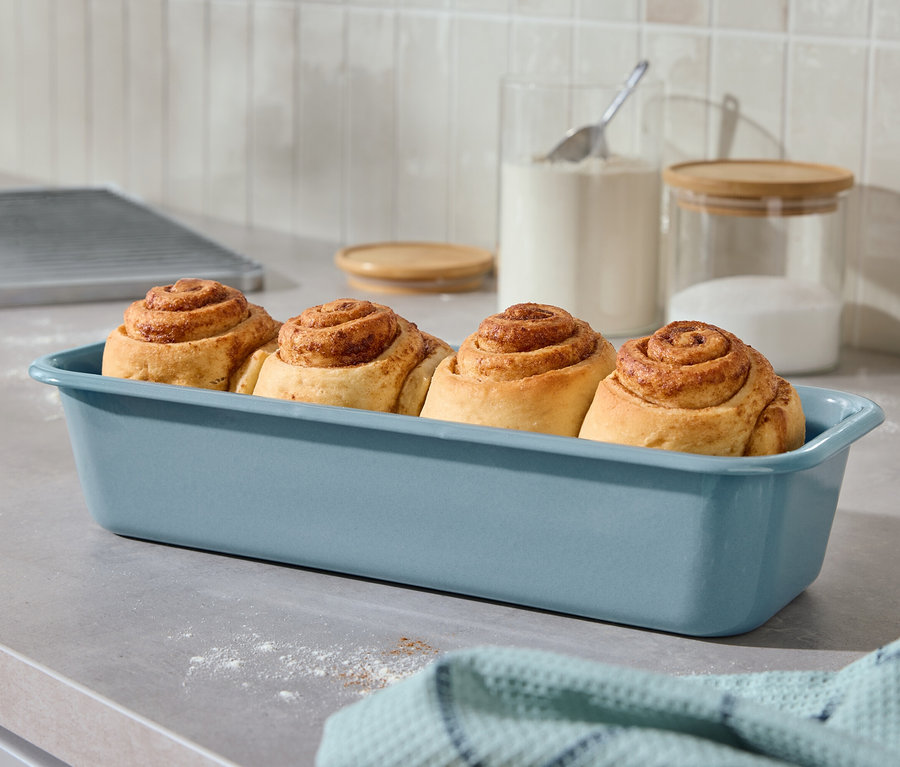 Čtyři skořicové rolky v modré zapékací míse na lince.