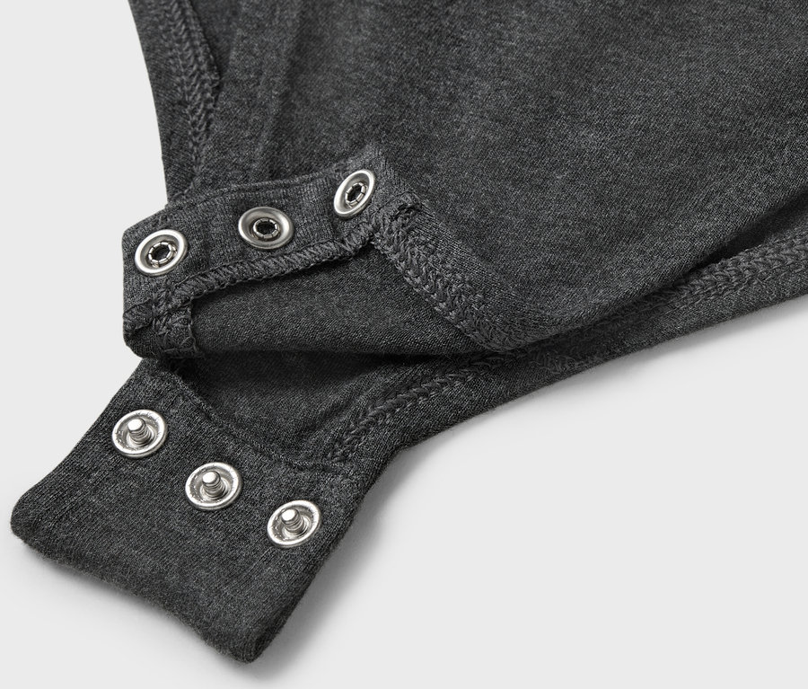 Detail šedého body s patentkami.