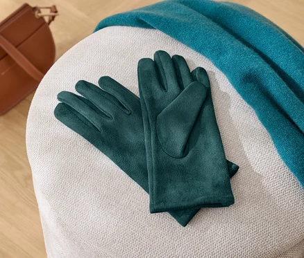 Na bílé stoličce leží zelené rukavice, modrá šála a hnědá kabelka.