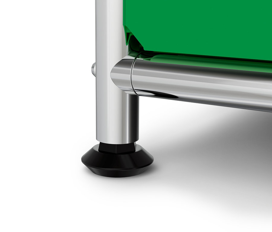 Detail chromové nohy s černou patkou a zelenou deskou na bílém pozadí.