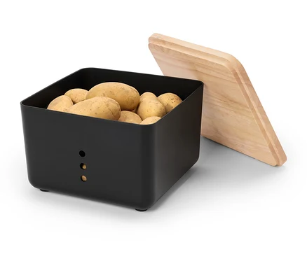 Černá krabice na brambory je plná brambor, vedle leží dřevěné víko.