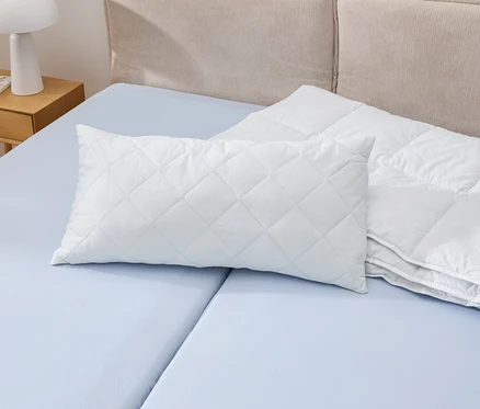 Bílý polštář Cell Solution® o rozměrech 80 x 40 cm leží na modré posteli vedle bílé peřiny.