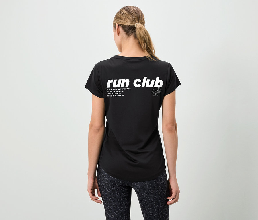 Pohled zezadu na ženu s culíkem v černém tričku s nápisem "run club" a vzorovaných legínách.