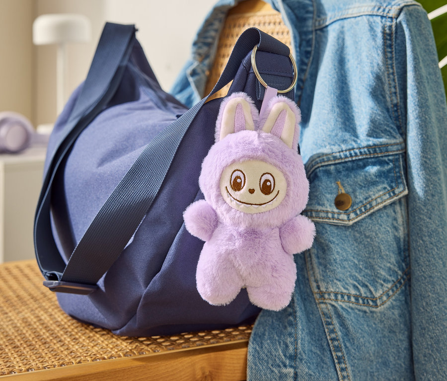 Modrá taška s přívěskem na klíče »Tchibobo« visí na džínové bundě.