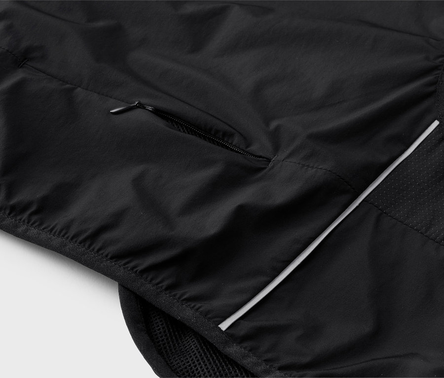 Detailní záběr na černou vestu s kapsou na zip a reflexními prvky.