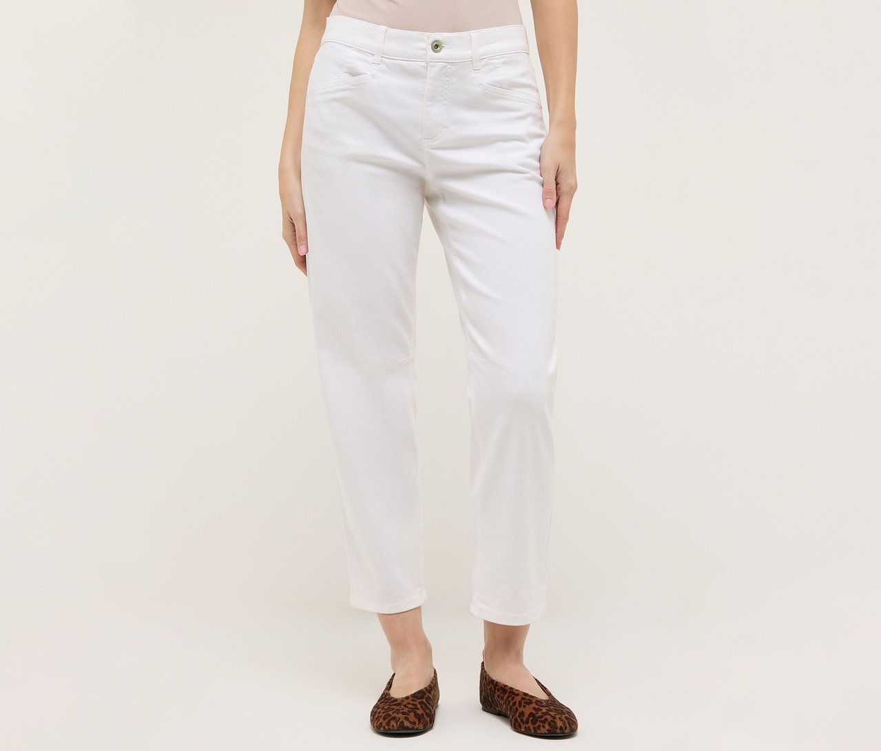 Žena má na sobě bílé džíny Angels »Evy Cool« O-shape a hnědé baleríny se zvířecím potiskem na světlém pozadí.
