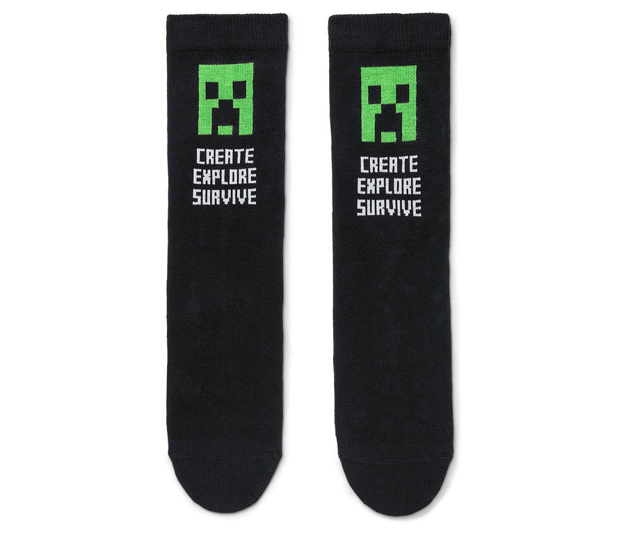 Dvě černé ponožky se zeleným obličejem Creepera z Minecraftu a textem „Create Explore Survive“.