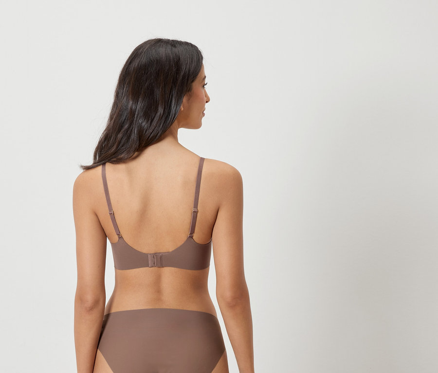 Pohled zezadu na ženu s tmavými vlasy, která má na sobě hnědou podprsenku a kalhotky.