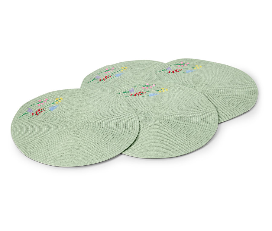 Čtyři kulaté, světle zelené prostírání s vyšívanými květinovými vzory leží na sobě.