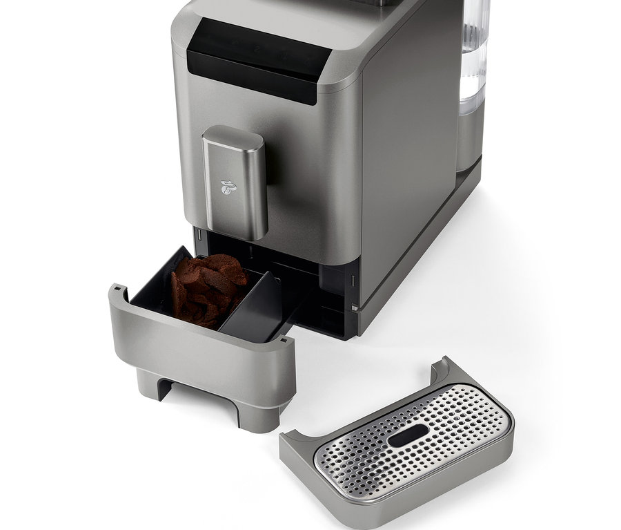 Detail plnoautomatického kávovaru »Esperto2 Caffè« v titanově stříbrné barvě s vyjmutou nádobou na kávovou sedlinu a odkapávací miskou.