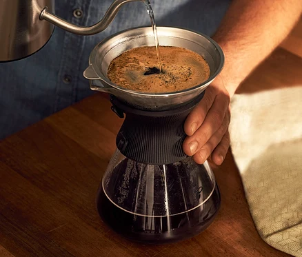 Muž nalévá vodu do skleněné karafy BEEM Pour Over 0,75 l s filtrem na kávu.