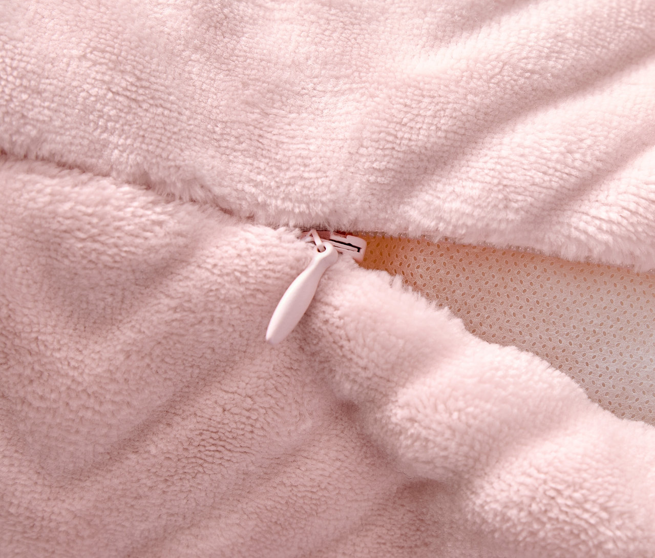 Detail růžového povlaku na polštář se zipem.