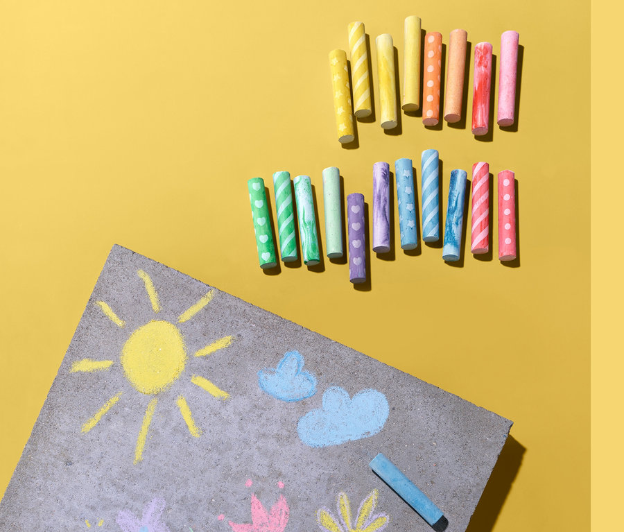 Žluté pozadí s kresbou slunce, mraků a květin a 20 vzorovanými křídami na kreslení na ulici.