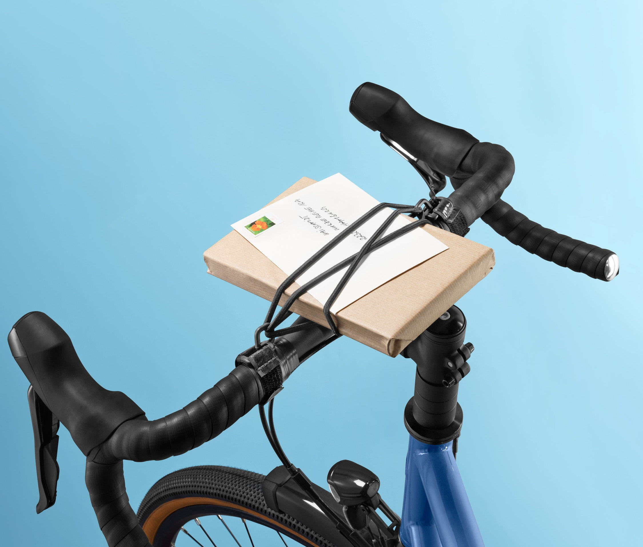 Balíček na řídítkách kola upevněný napínací gumou na řídítka.