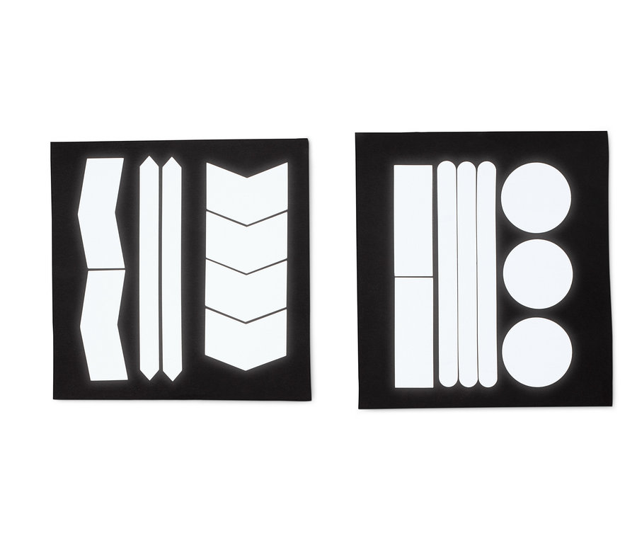 Dva černé archy s reflexními samolepkami různých tvarů: pruhy, šípy a kruhy.