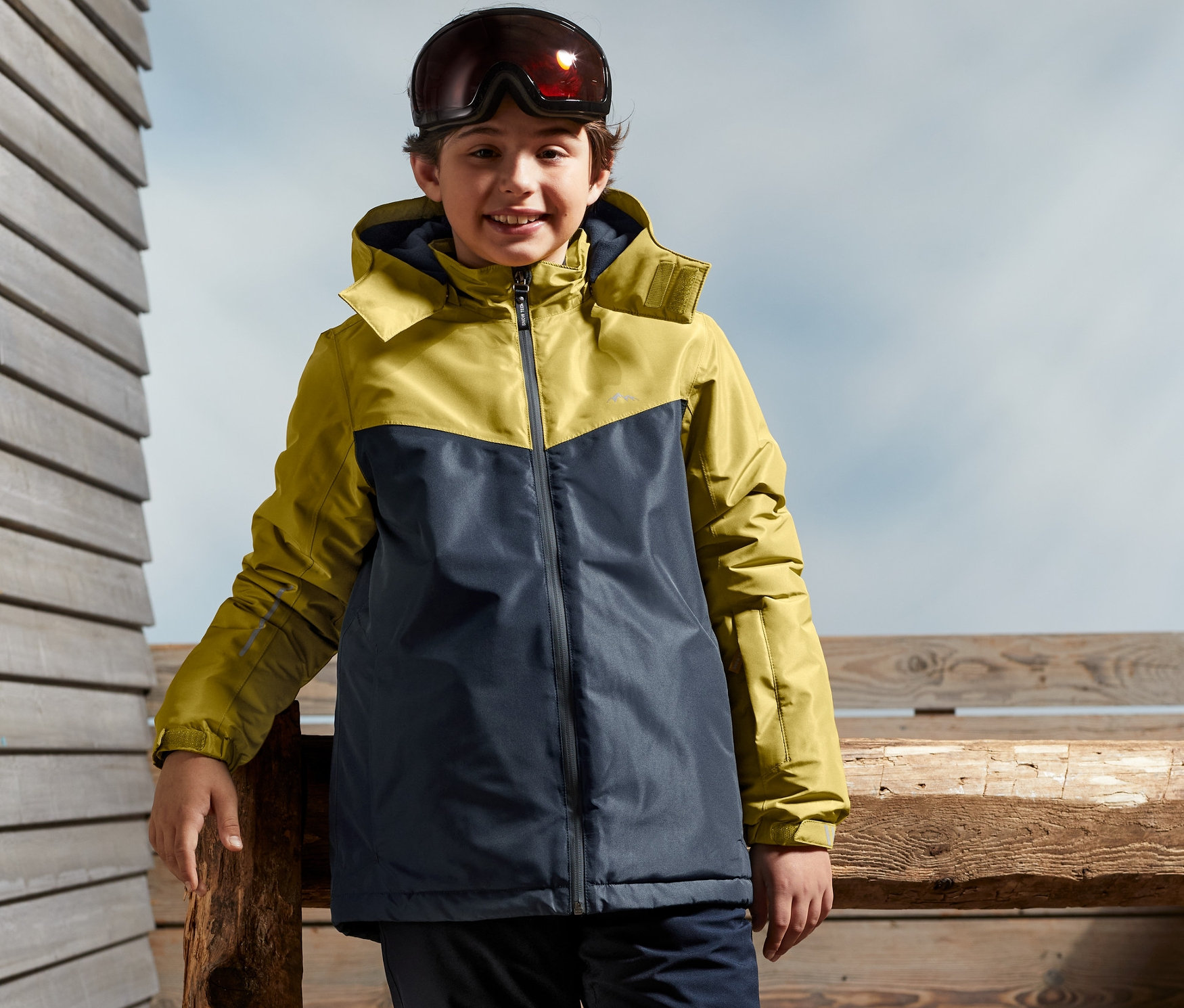 Chlapec stojí venku a má na sobě lyžařskou bundu.