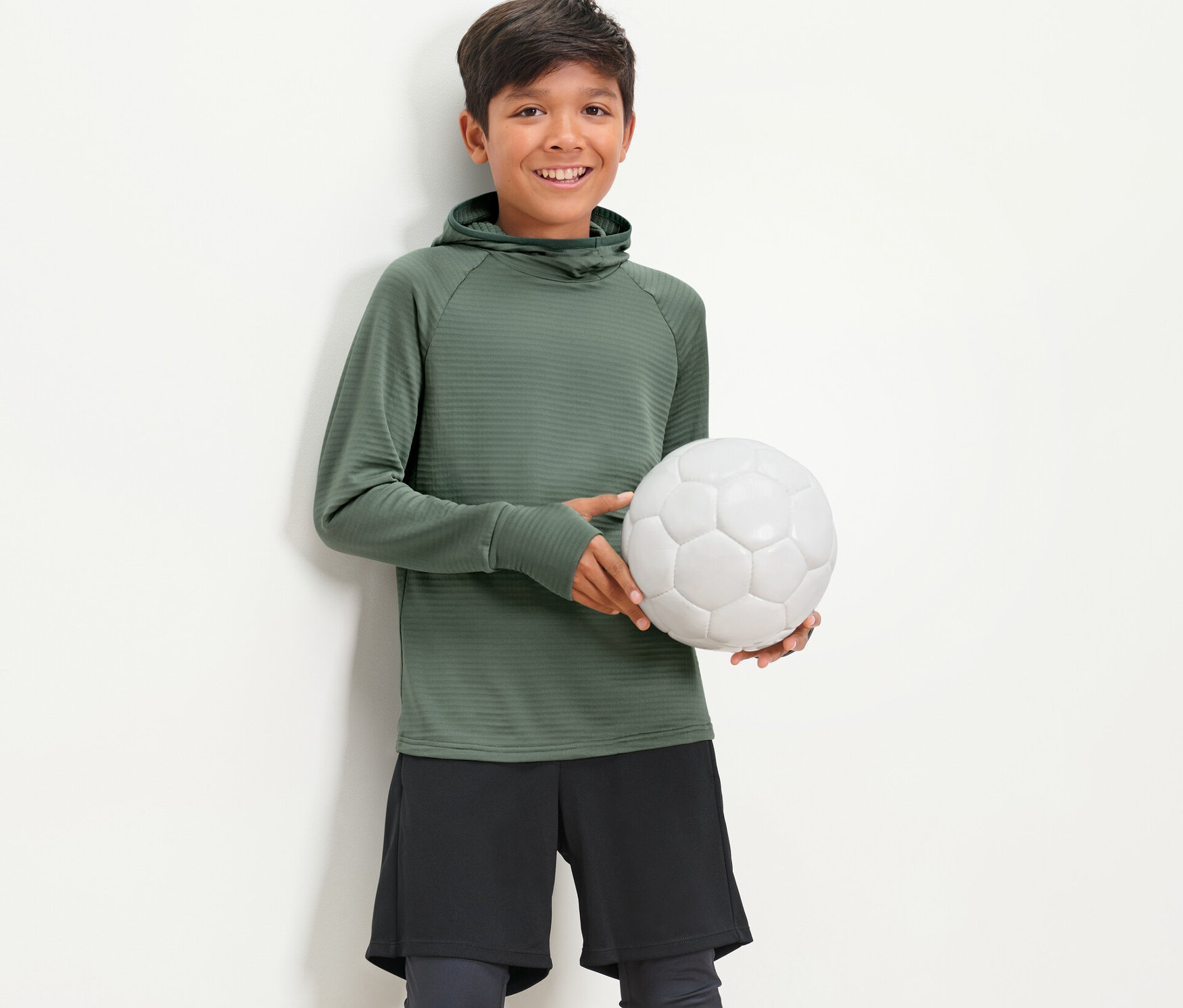 Chlapec drží fotbalový míč a má na sobě dětské funkční triko s dlouhým rukávem.