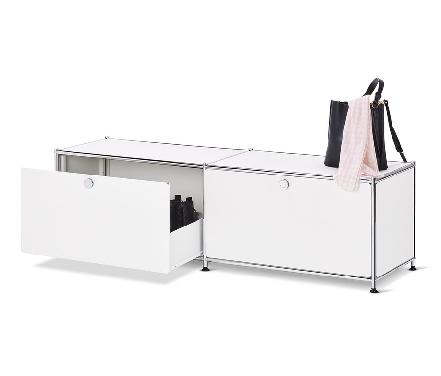 Otevřená bílá kovová nízká skříňka CN3 se zásuvkami s botami uvnitř a kabelkou a šátkem na ní.