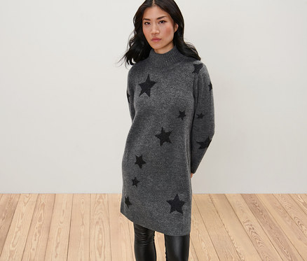 Žena pózuje v pletených šatech s rolákem.